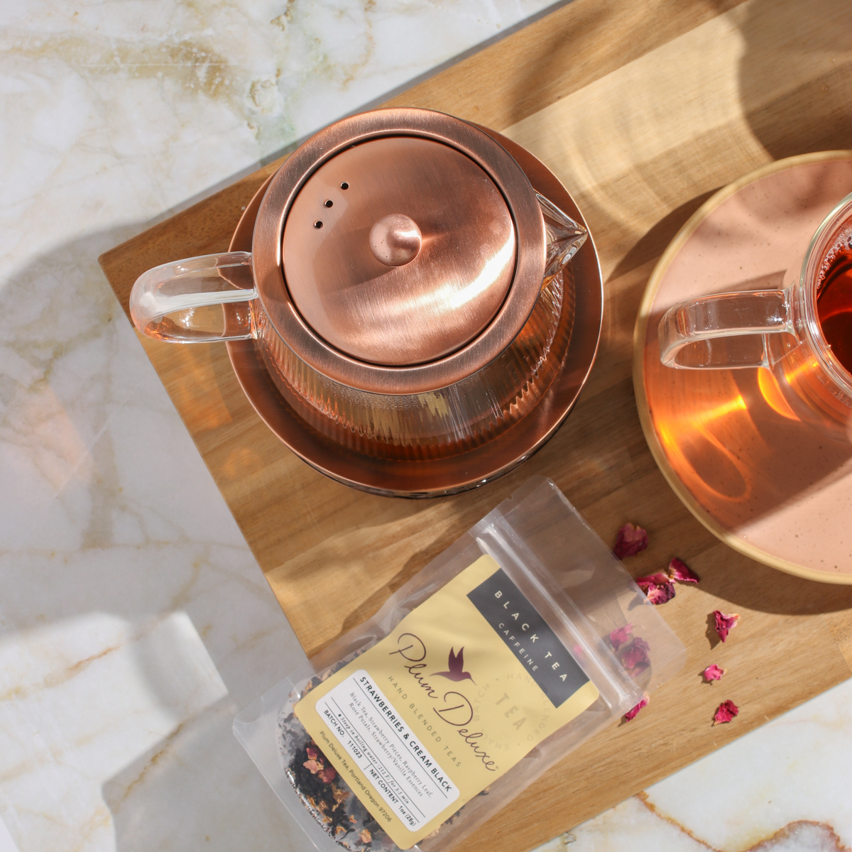 Copper Rose glass teapot with warmer from Plum Deluxe Tea, featuring a clear glass body and elegant copper rose accents.