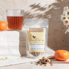 Cozy Tranquil Dream herbal tea by Plum Deluxe with rosehip and spearmint in a tea cup on a cozy table setting.