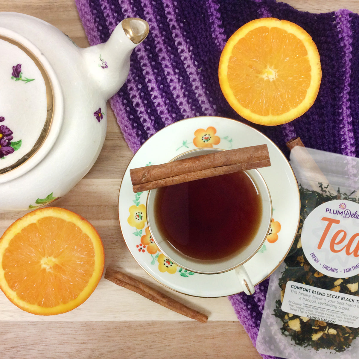 Decaf Comfort Blend Black Tea by Plum Deluxe with orange and cinnamon, shown in a tea infuser basket with loose tea leaves.