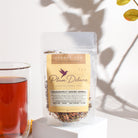 Herbal tea with vibrant pink and red dragonfruit pieces in a clear glass cup, showcasing Plum Deluxe Dragonfruit Desire Herbal Tea.