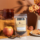 Black tea with vanilla and caramel from Plum Deluxe Halloween Blend, featuring a steaming mug with tea leaves and cozy fall setting.