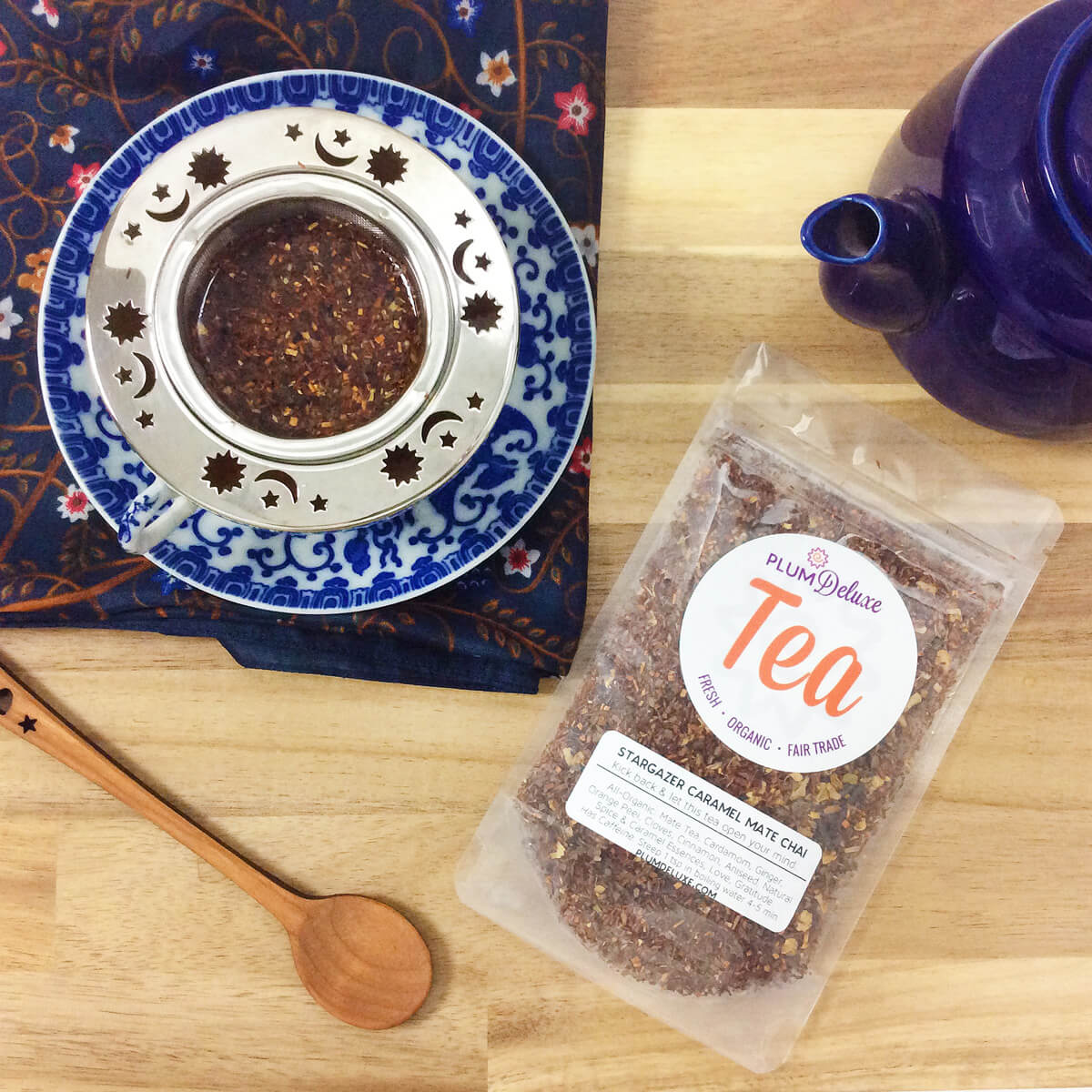 A steaming cup of Stargazer Caramel Maté Chai tea by Plum Deluxe Tea with a creamy caramel color in a white mug.