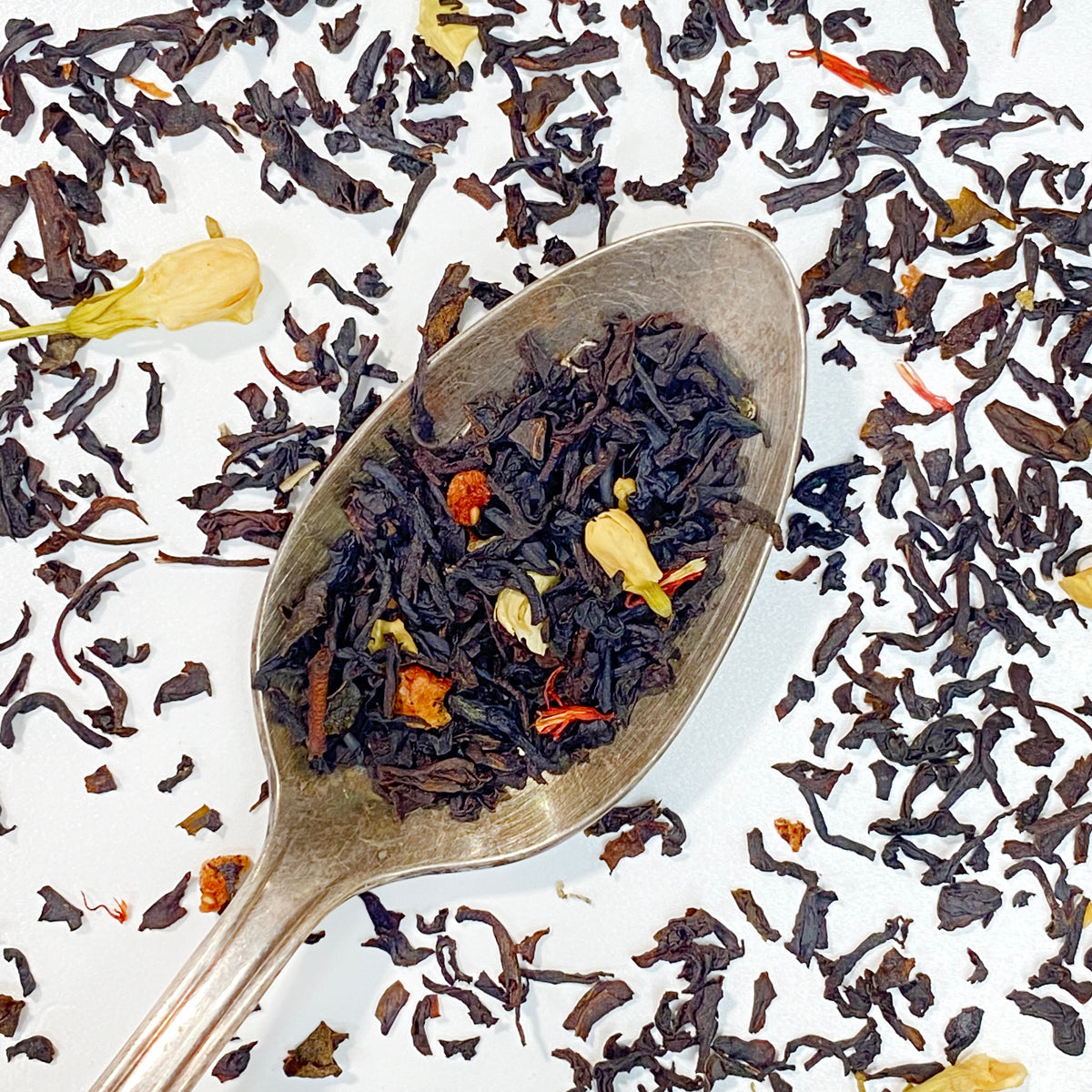 Black tea from Plum Deluxe with roasted strawberry brulee flavor, showcasing dried strawberry pieces and rich tea leaves.