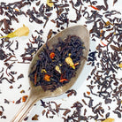 Black tea from Plum Deluxe with roasted strawberry brulee flavor, showcasing dried strawberry pieces and rich tea leaves.
