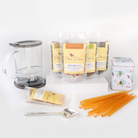 Plum Deluxe Tea Ultimate Hot Tea Bundle including assorted teas, sweets, tea scoop, storage tin, and tea maker on a wooden table.