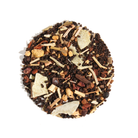 A warm cup of Plum Deluxe Tea's Uplifting Coconut Chai with coconut flakes and chai spices on a cozy wooden table.