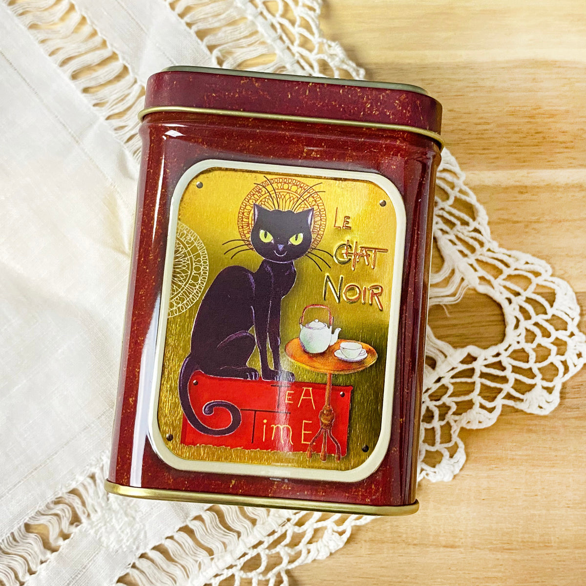 Le Chat Noir tea tin by Plum Deluxe Tea featuring a vintage black cat design on a round metal container.