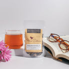 Cup of Plum Deluxe Reading Nook Tea Blend with rose, lavender, and chamomile in a cozy setting, showcasing the herbal tea mix.