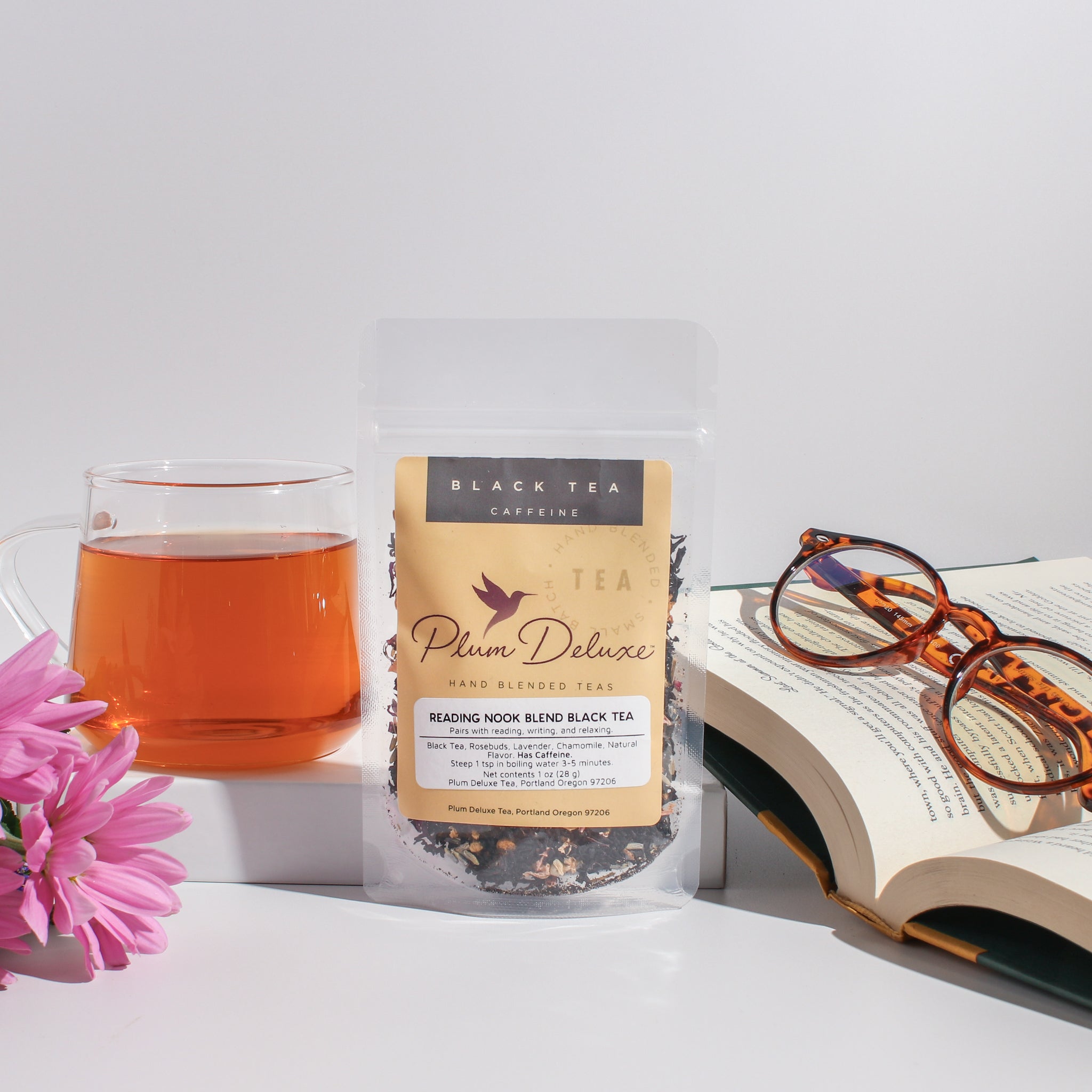 Cup of Plum Deluxe Reading Nook Tea Blend with rose, lavender, and chamomile in a cozy setting, showcasing the herbal tea mix.