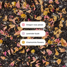 Plum Deluxe Reading Nook Tea Blend with rose, lavender, and chamomile in a tea bag on a wooden table.