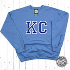 Powder blue KC Glitter applique crewneck sweatshirt by The Graphic Tee with sparkling design and comfortable fit.