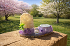 Amethyst and druzy geode freeform sphere holder with natural crystalline textures and purple hues on a neutral surface.