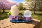 Amethyst and druzy geode freeform sphere holder with crystal formations on a natural stone base.