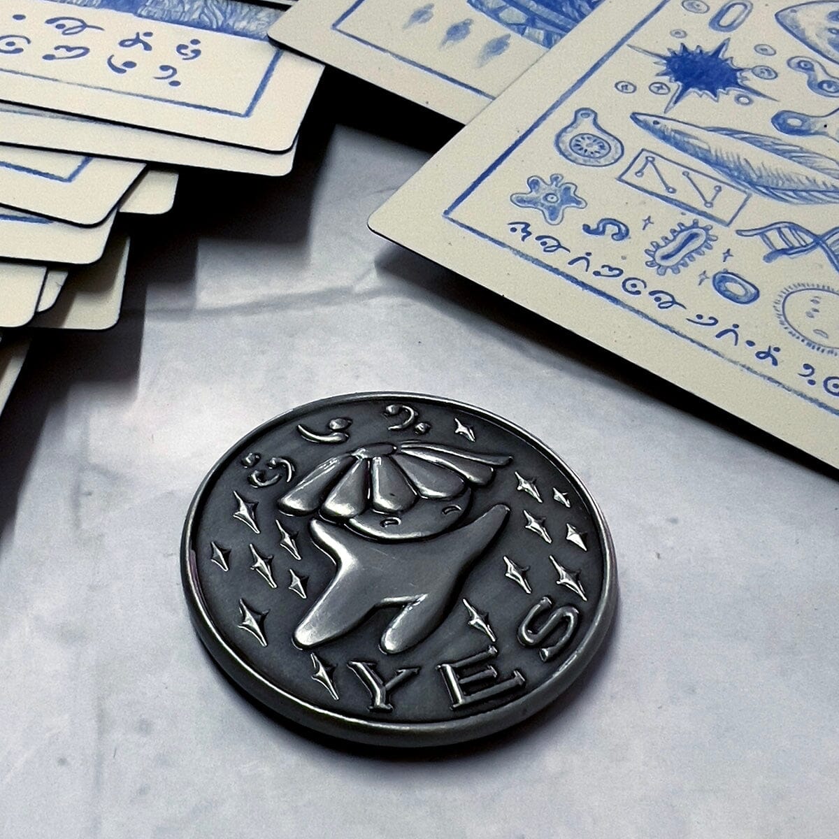 Prisma Visions Kuzo Yes/No Coin featuring a metallic design with engraved Yes and No symbols on its surface.