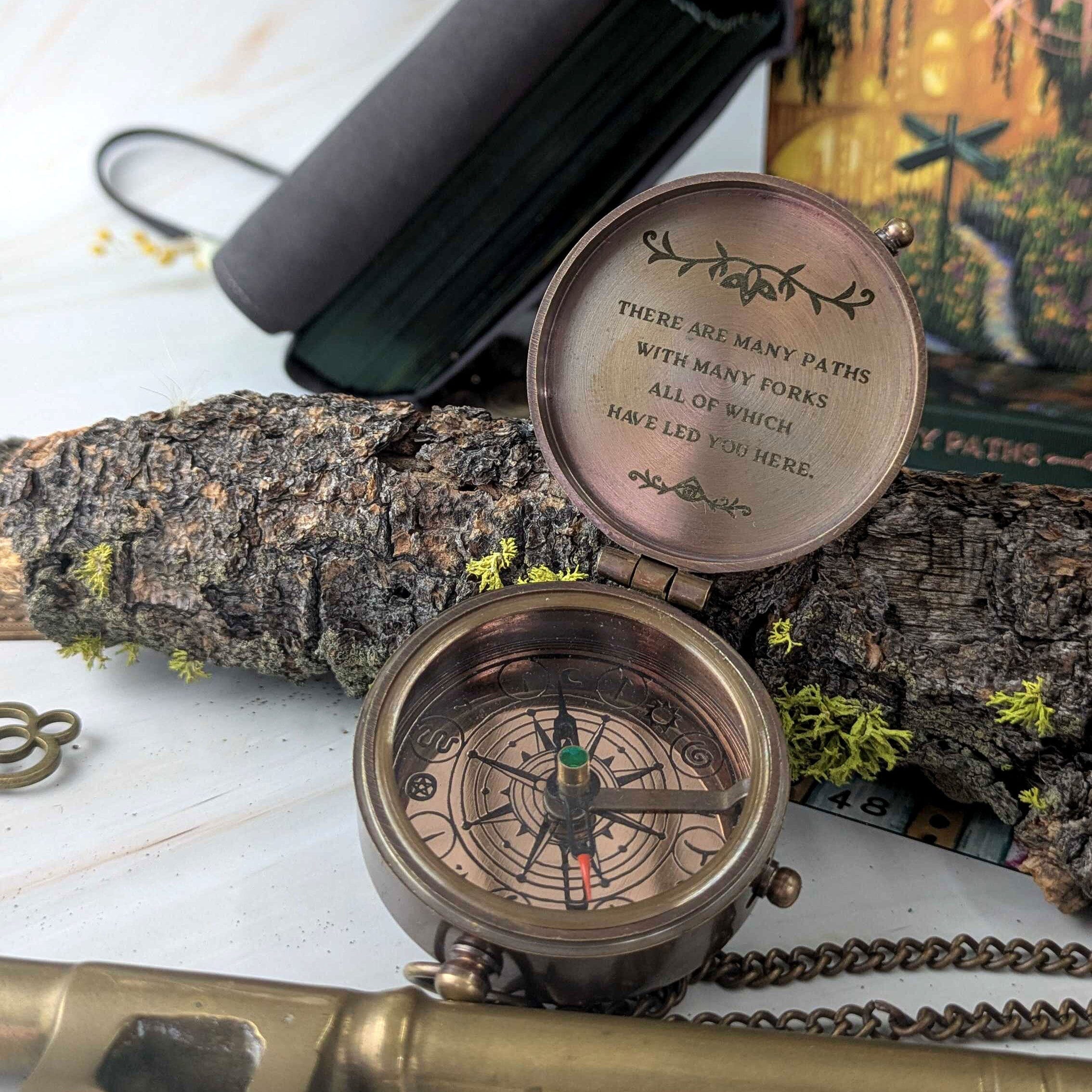Prisma Visions Compass of Many Paths, a detailed metal compass with intricate design and directional markings, on a neutral background.