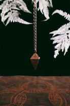 Green Glyphs Pendulum by Prisma Visions, featuring a detailed green gemstone with intricate glyph designs, hanging from a silver chain.