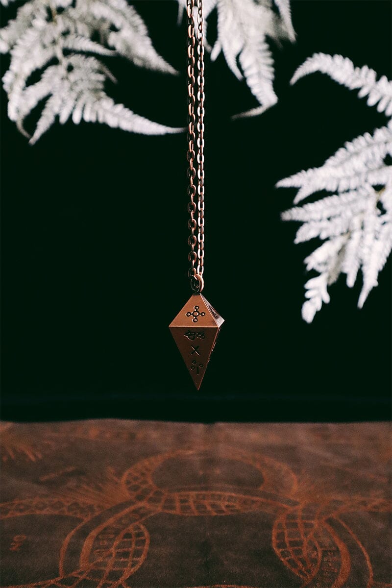 Green Glyphs Pendulum by Prisma Visions, featuring a detailed green gemstone with intricate glyph designs, hanging from a silver chain.
