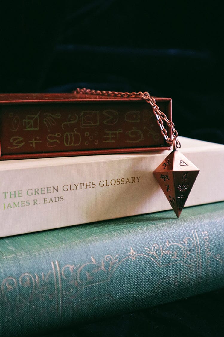 Green Glyphs Pendulum by Prisma Visions, featuring a detailed green design on a sleek pendulum with a silver chain.