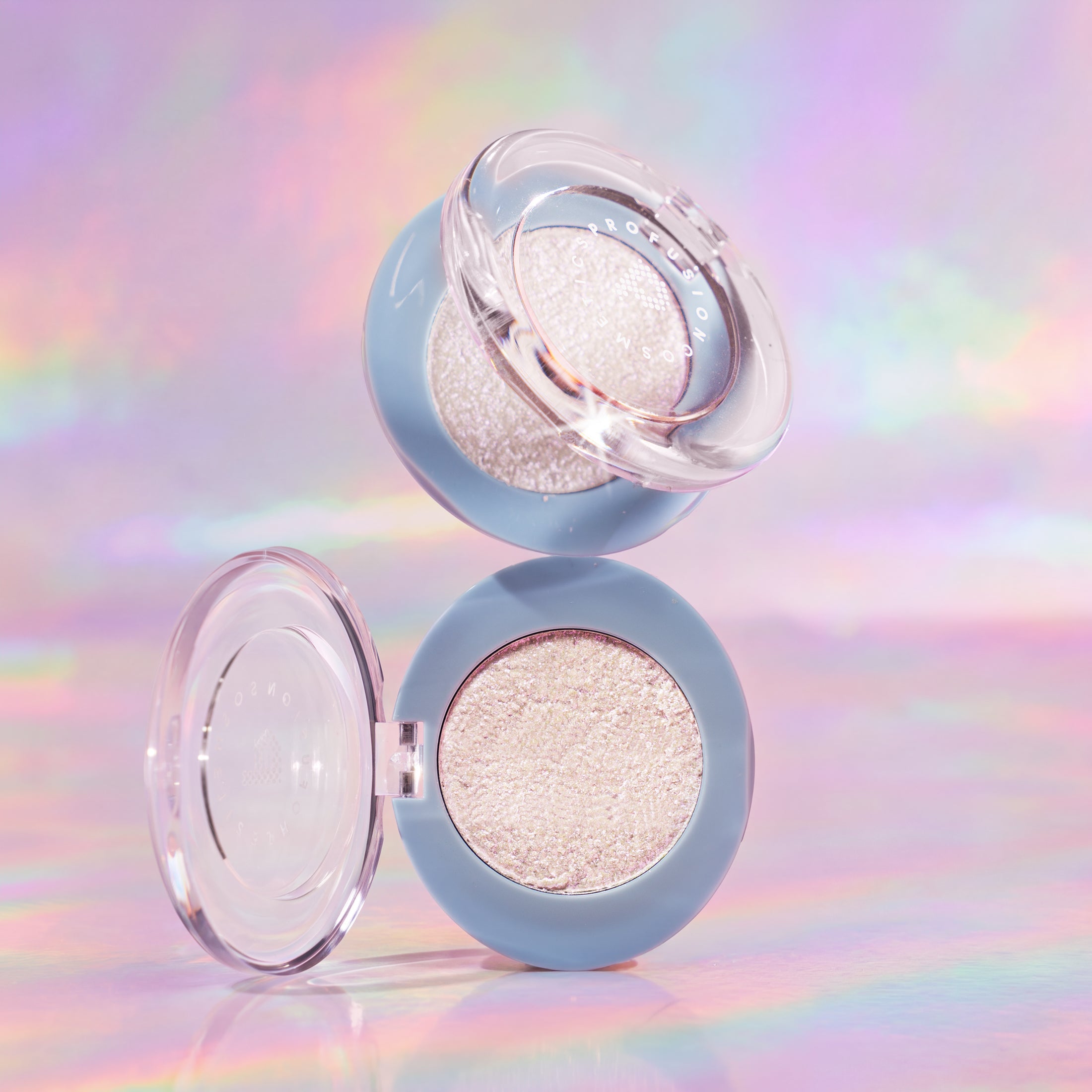 Profusion Cosmetics Bouncy Glow Frosted Holo Face Highlighter with a shimmering, holographic finish on a reflective surface.