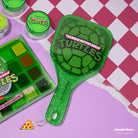 Profusion Cosmetics TMNT face handheld mirror showing a detailed face design in a sleek, portable mirror style.