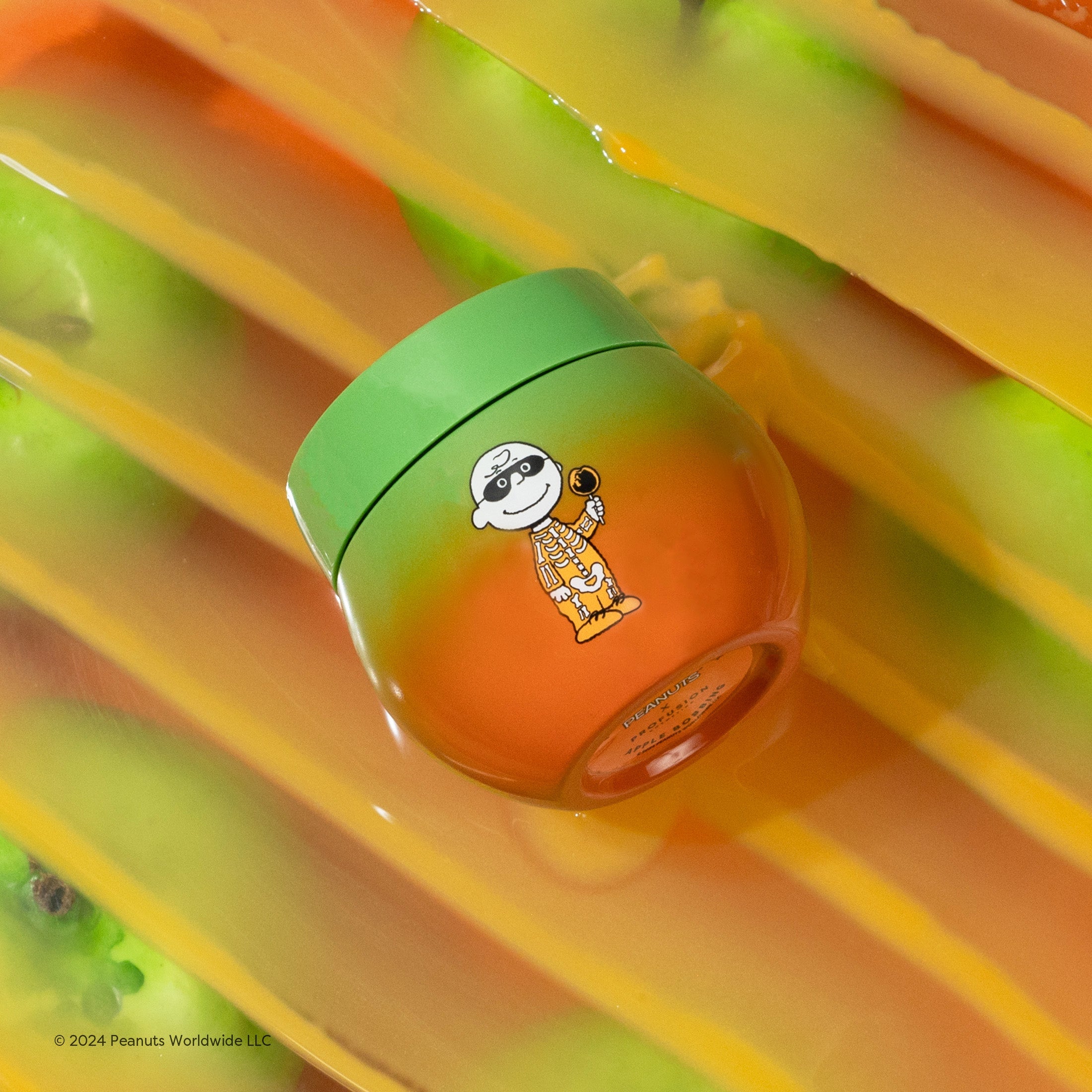 Profusion Cosmetics Peanuts Halloween apple bobbing overnight lip mask applied on lips with festive Halloween-themed packaging.