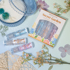 Profusion Cosmetics Petal Perfect Secret Garden Nourishing Lip Oil Set with floral packaging and glossy lip oils displayed.