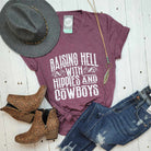 White SS graphic tee by The Graphic Tee featuring bold "Raising Hell With The Hippies And The Cowboys" design on front.