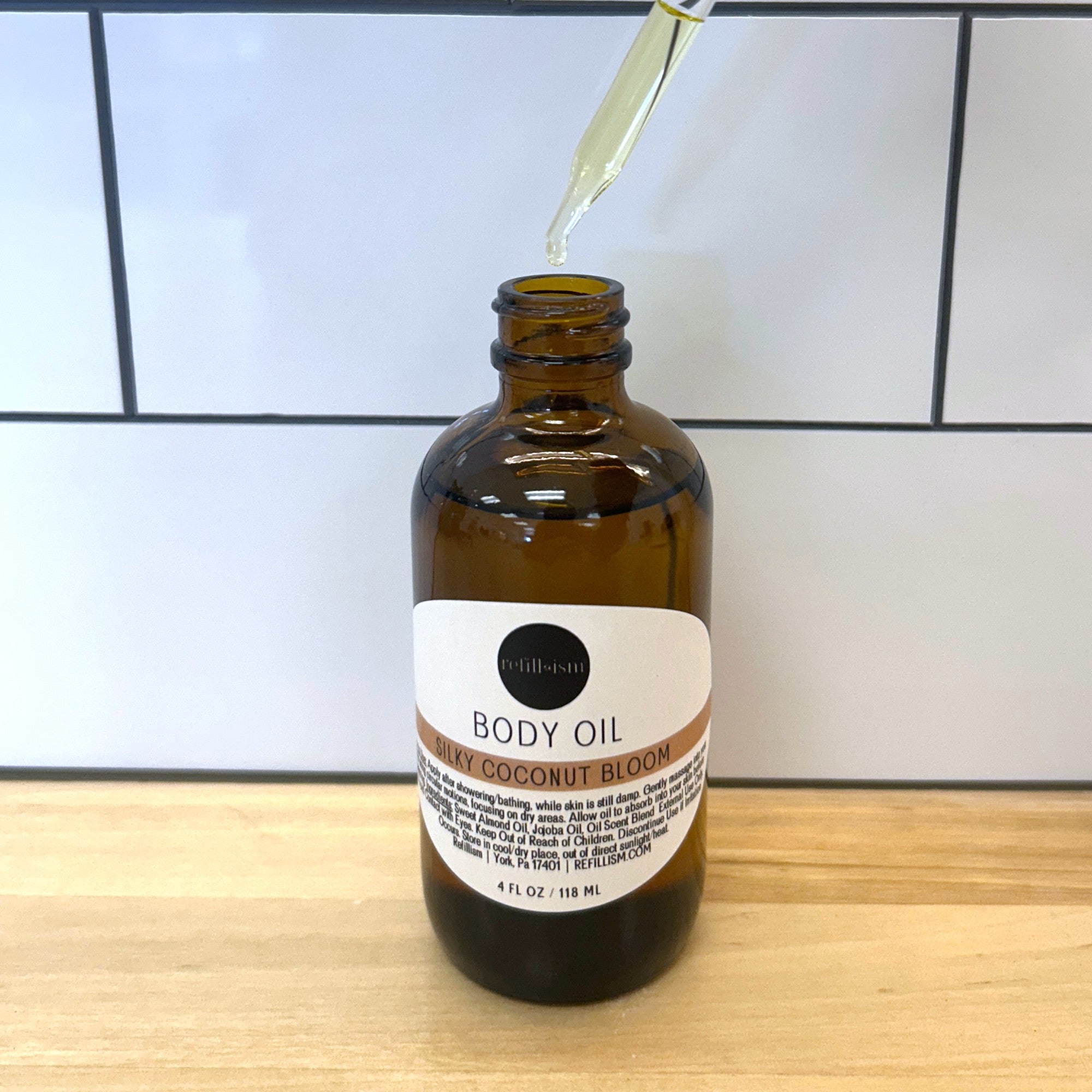 Refillism Silky Coconut Bloom Body Oil in a sleek bottle, highlighting its nourishing, silky texture for personal care.