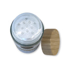 Refillism dry shampoo with lemongrass and verbena in a clear glass shaker bottle, ideal for quick hair refreshment.
