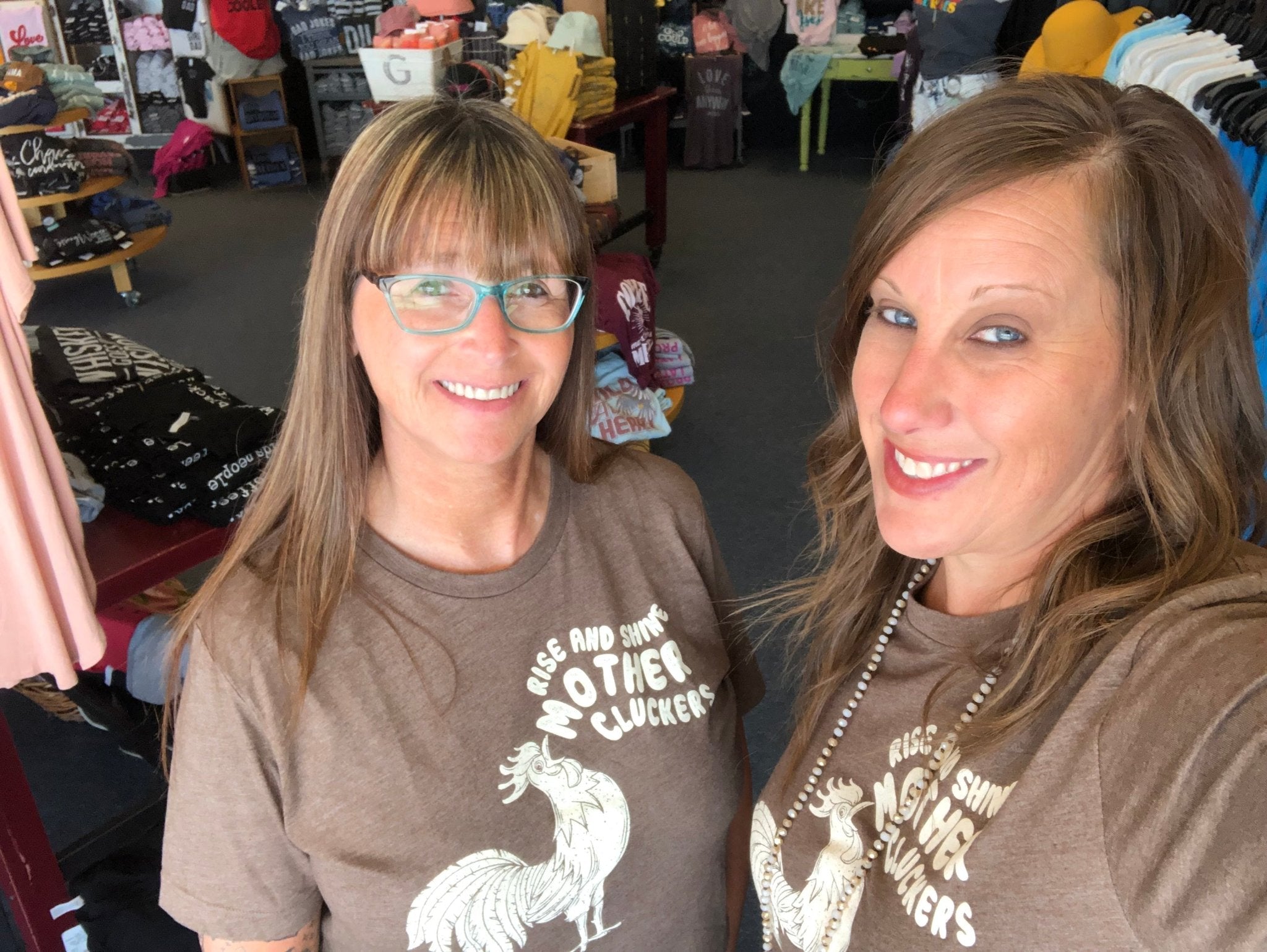 Unisex graphic tee featuring "Rise and Shine Mother Cluckers" slogan, casual style, with colorful rooster illustration.