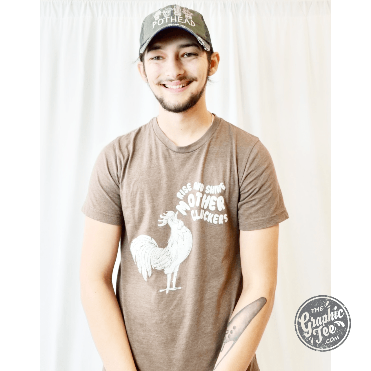 Unisex SS graphic tee with "Rise and Shine Mother Cluckers" slogan in bold black text on soft cotton fabric.