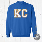 Royal KC Glitter Applique Crewneck Sweatshirt from The Graphic Tee featuring glitter details on a cozy crewneck sweatshirt.