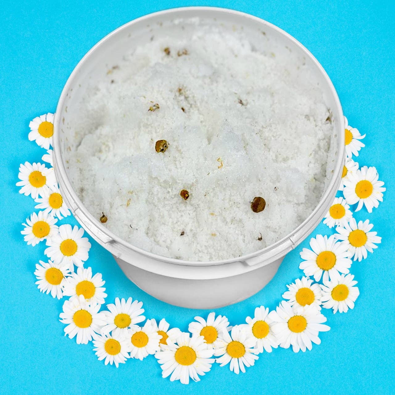 Sage & Stone Apothecary exfoliating chamomile flower scrub in a jar, showing the textured scrub with chamomile flowers for body care.