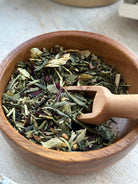 Herbal hair stimulation tea blend by Sage & Stone Apothecary in a glass jar with tea bags and loose herbs on a wooden surface.