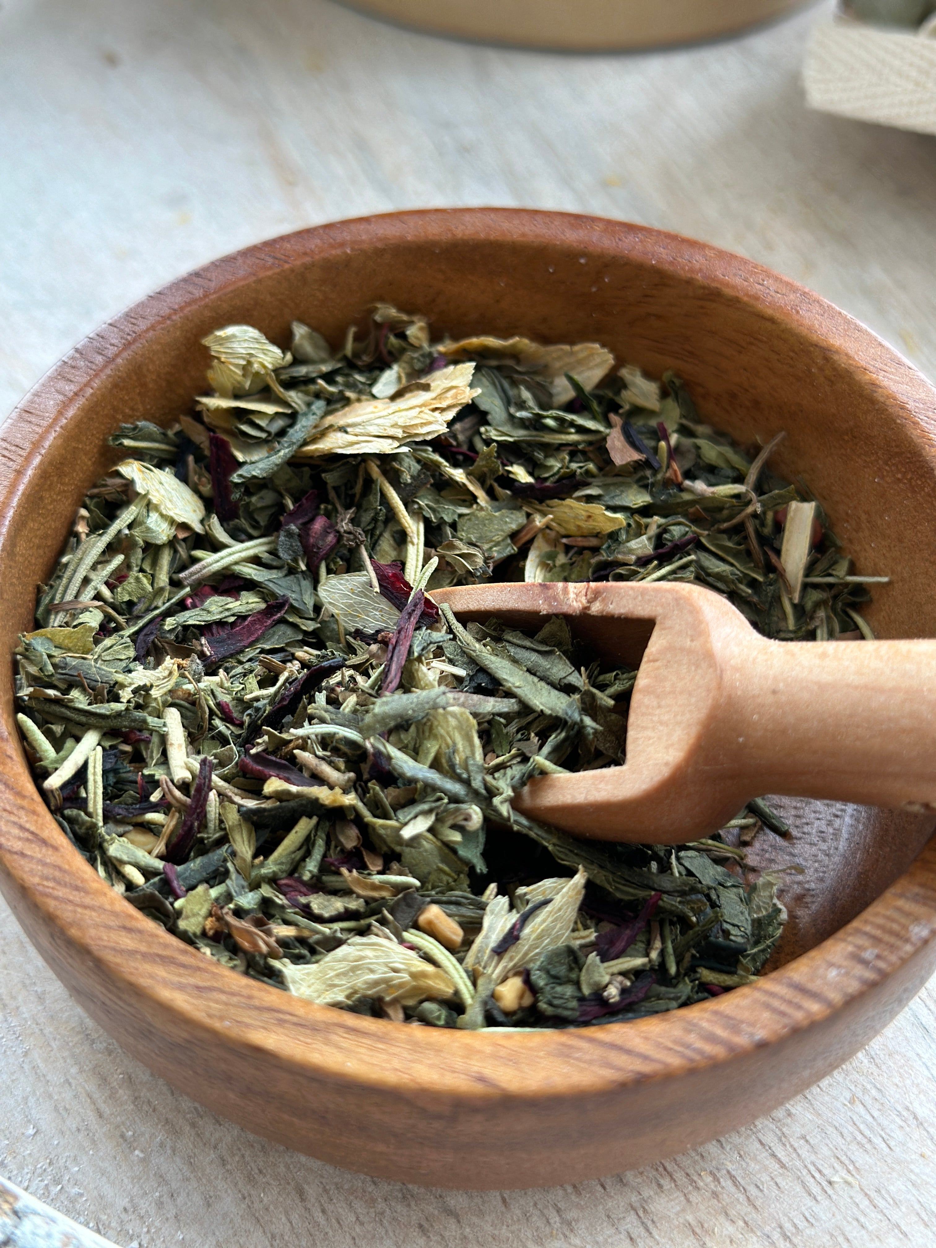 Herbal hair stimulation tea blend by Sage & Stone Apothecary in a glass jar with tea bags and loose herbs on a wooden surface.