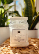 Magnesium chloride flakes in a clear jar, used for body care and wellness, by Sage & Stone Apothecary.