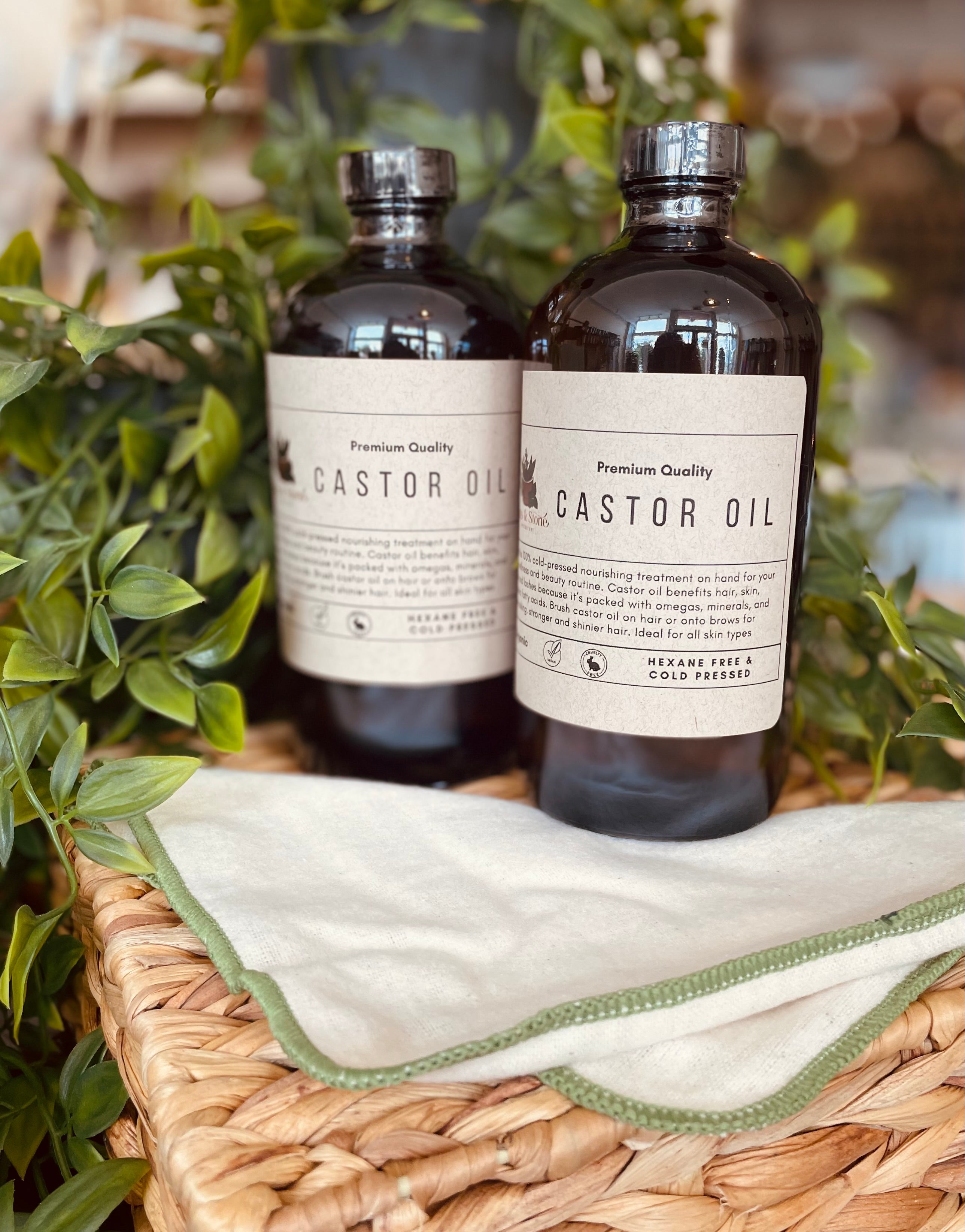 Organic cold pressed castor oil bottle from Sage & Stone Apothecary, displayed in a clear glass container for body care and wellness.