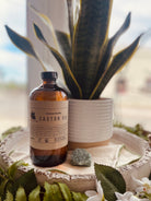 Organic cold pressed castor oil bottle from Sage & Stone Apothecary, used for body care and wellness, displayed on a wooden surface.