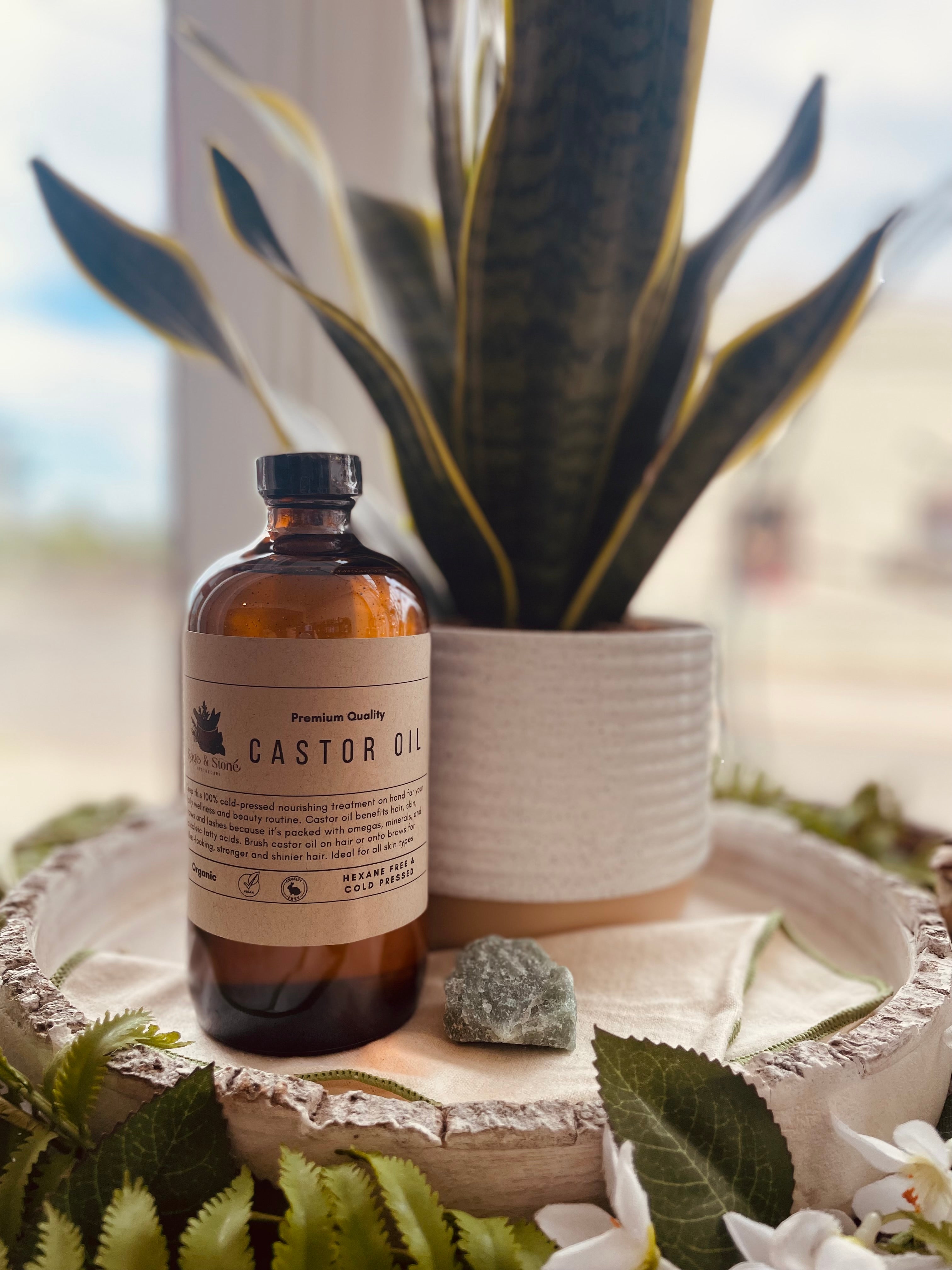 Organic cold pressed castor oil bottle from Sage & Stone Apothecary, used for body care and wellness, displayed on a wooden surface.