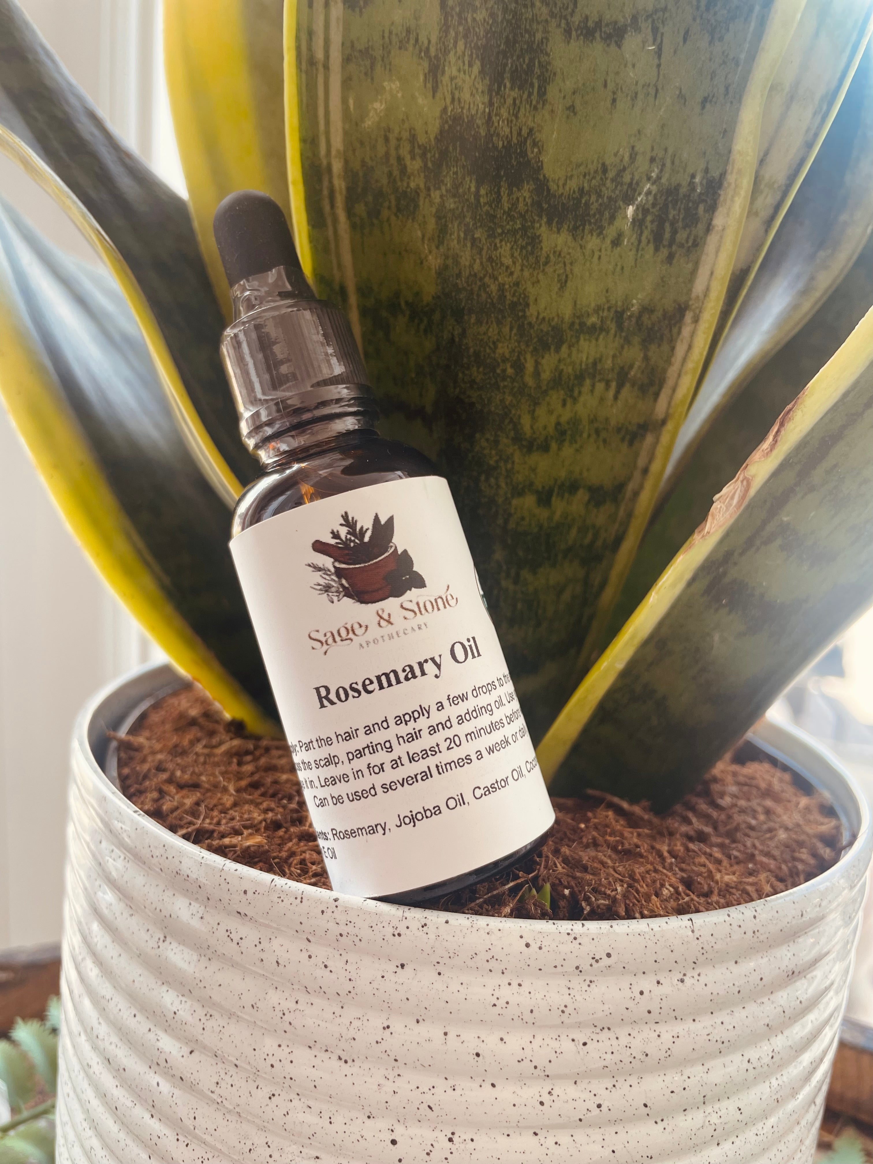Sage & Stone Apothecary rosemary oil bottle for body care and wellness, with fresh rosemary sprigs beside it.