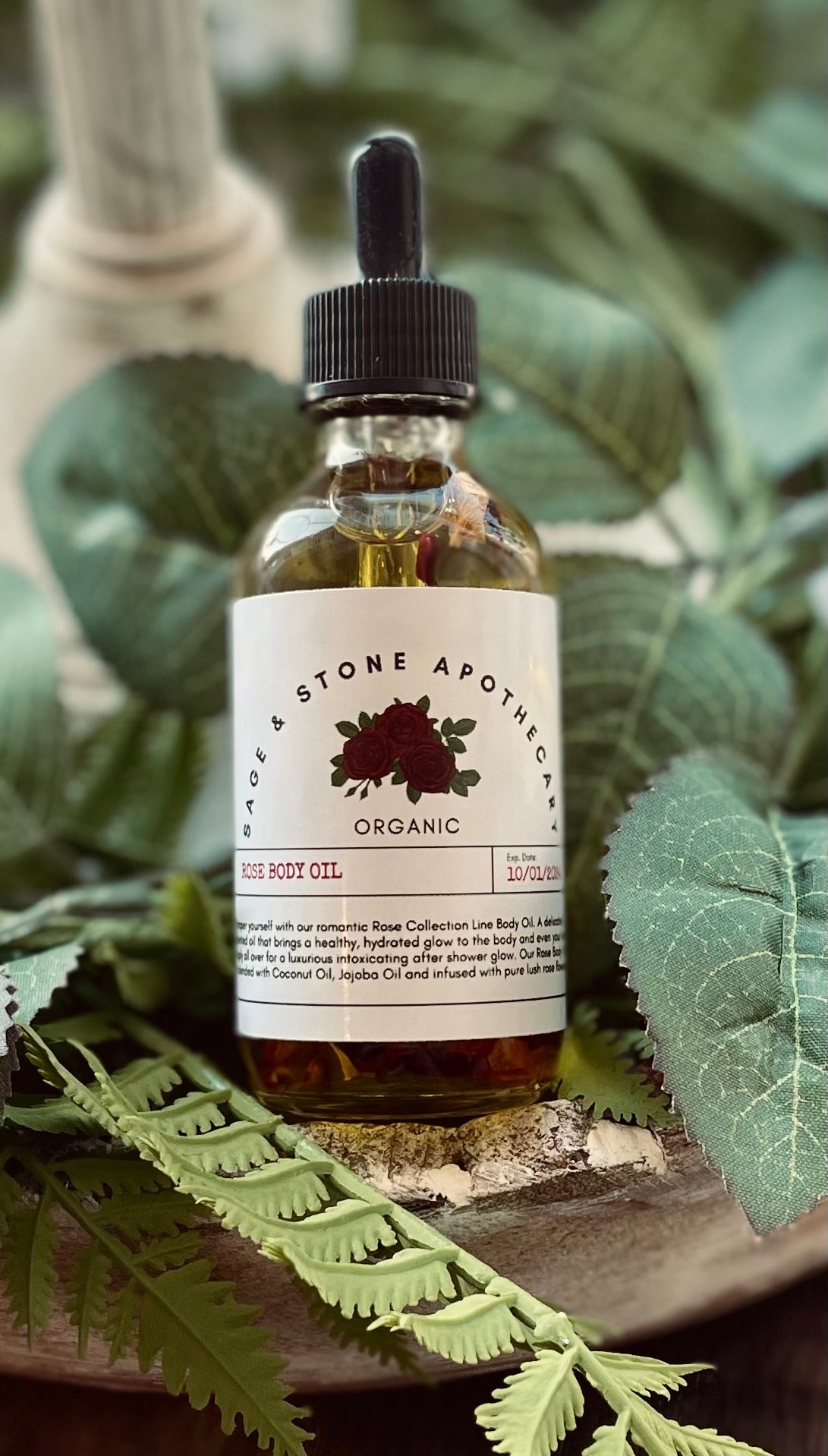 Bottle of Sage & Stone Apothecary rose body oil with a sleek glass container and a rose scent label.