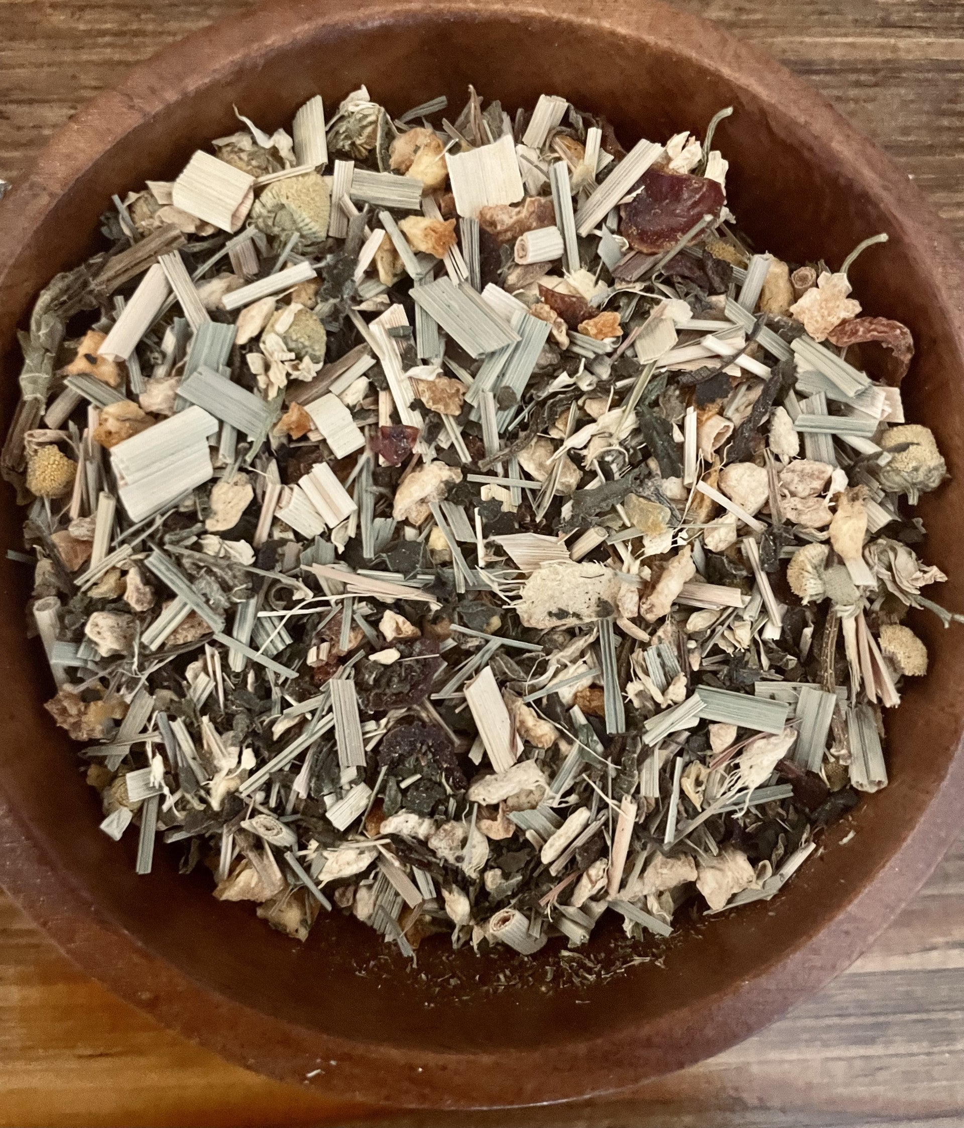 Herbal anti-allergy tea by Sage & Stone Apothecary in a glass mug with fresh herbs and tea leaves.