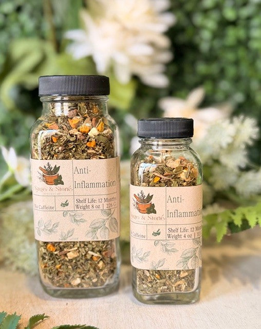 Sage & Stone Apothecary anti-inflammation herbal tea with dried herbs in a glass jar and a steaming cup of tea on a wooden table.
