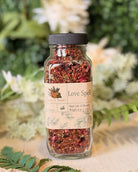 8 oz Love Spell herbal tea from Sage & Stone Apothecary featuring a blend of dried herbs in a clear jar.