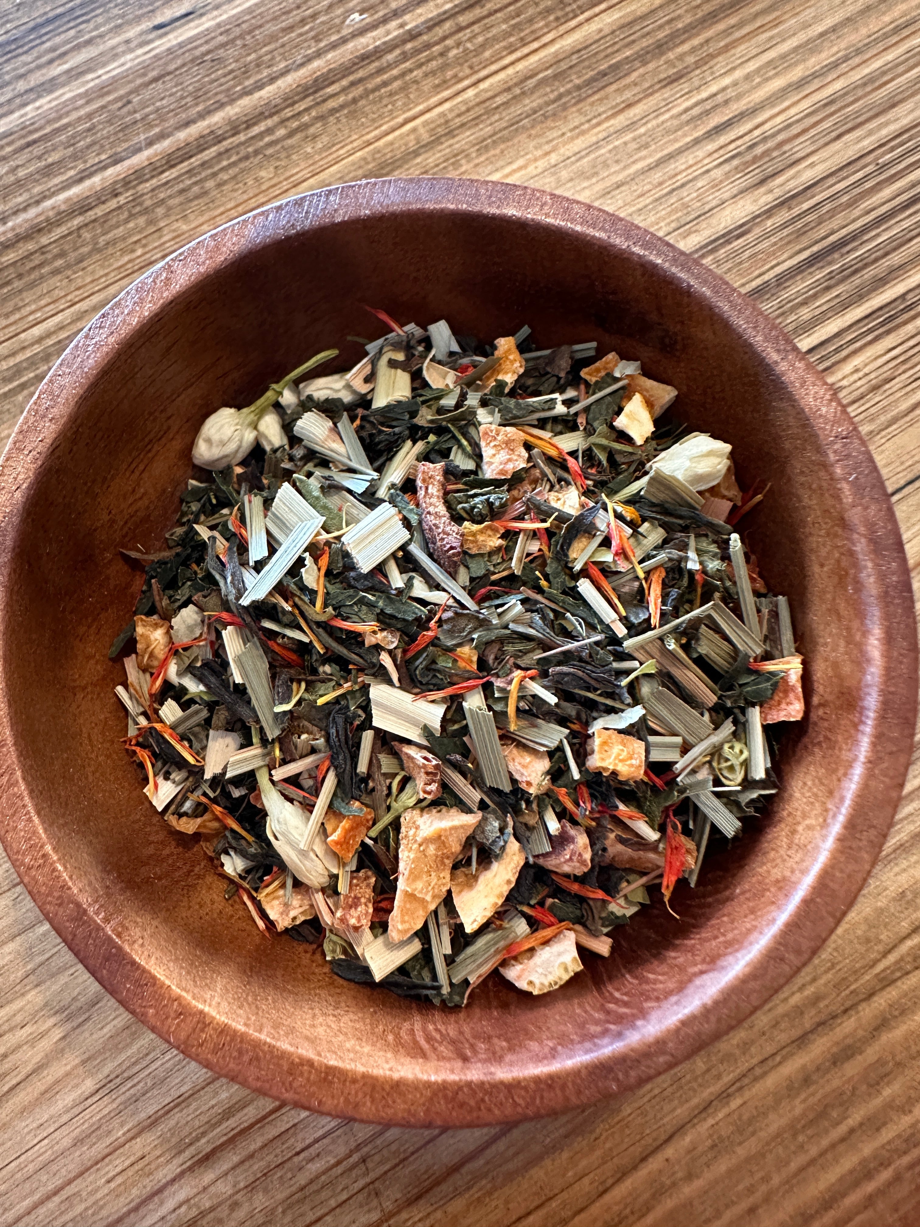 Cup of Moon Goddess herbal tea by Sage & Stone Apothecary with dried herbs and moon symbolism on the packaging.
