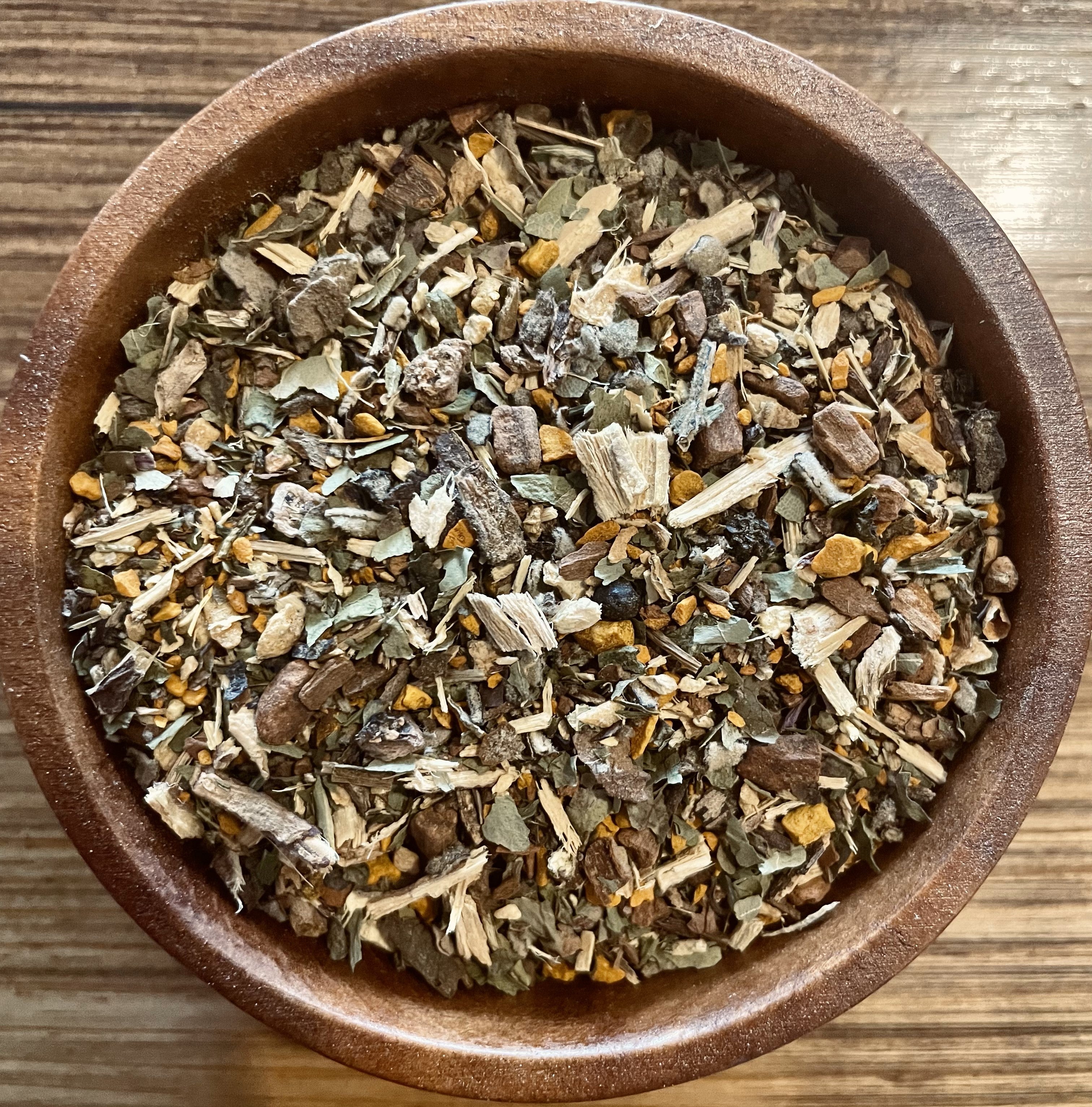 Sage & Stone Apothecary Decongest Blend tea in a clear glass cup, showing herbal tea with visible herbs and steam.