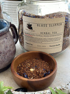 Glass Slipper Tea by Sage & Stone Apothecary in a clear glass teapot with blooming tea flowers inside.