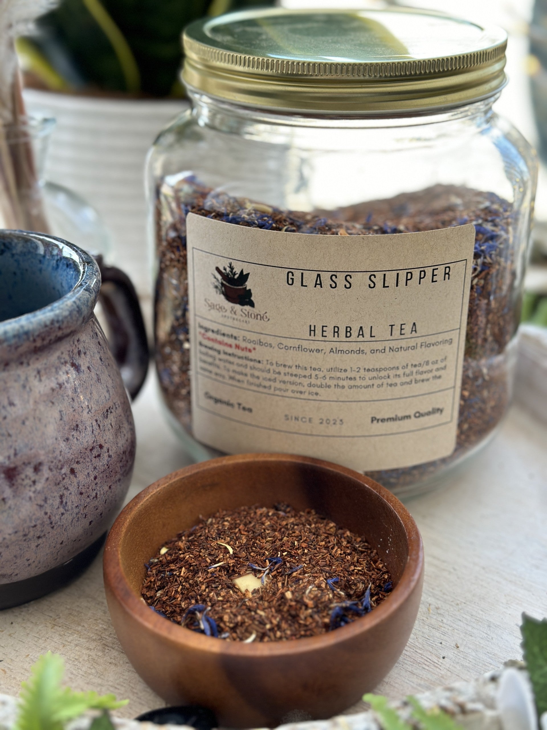 Glass slipper-shaped tea infuser from Sage & Stone Apothecary, showcasing its clear glass design and elegant shape.