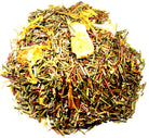 A cup of Peach Dream tea by Sage & Stone Apothecary with fresh peach slices and blooming chamomile flowers on a rustic wooden table.