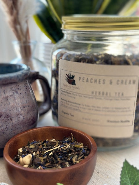 A cup of Peaches & Cream tea by Sage & Stone Apothecary with fresh peach slices and creamy tea in a white ceramic mug.